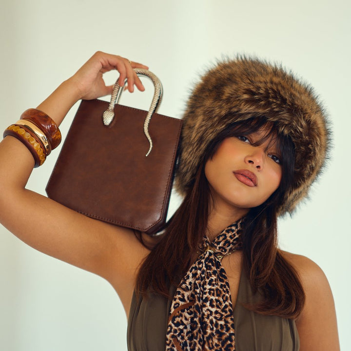 Joie bag held up beside a fur hat